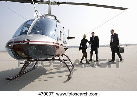 Businesswoman greeting two businessman by a helicopter View Large Photo Image Stock Photo - Businesswoman greeting two businessman by a helicopter. Fotosearch