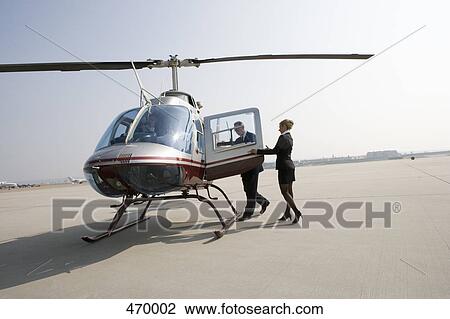Woman assisting a businessman board a helicopter View Large Photo Image Stock Image - Woman assisting a businessman board a helicopter. Fotosearch
