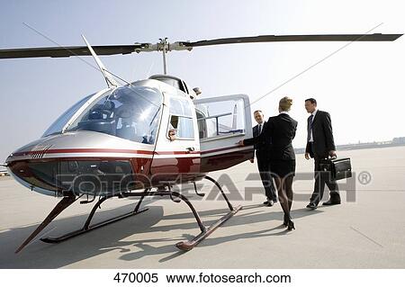 Woman assisting businessmen board a helicopter View Large Photo Image Stock Photography - Woman assisting businessmen board a helicopter. Fotosearch