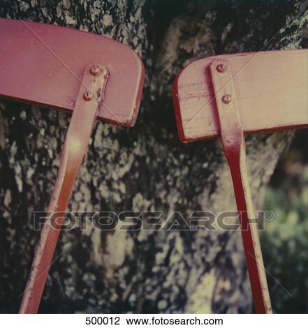 Stock Image - Detail of two chairs leaning against a tree. Fotosearch