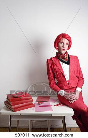 Stock Image - Drag queen posing on a desk. Fotosearch