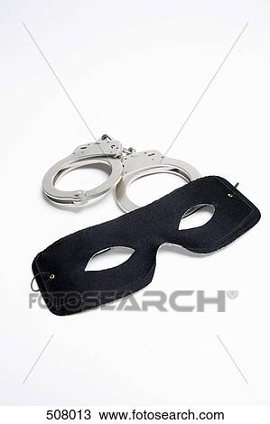Stock Image - A pair of handcuffs and a black mask. Fotosearch