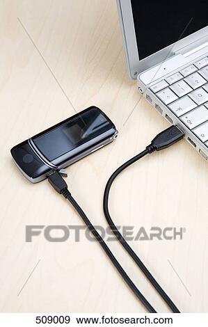 A mobile phone connected to a laptop computer View Large Photo Image Stock Photo - A mobile phone connected to a laptop computer. Fotosearch