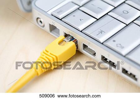 Stock Photograph - A network connection cable plugged into a laptop. Fotosearch