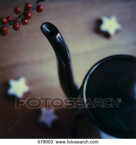Stock Image - A black teapot with star shaped candles and red berries. Fotosearch