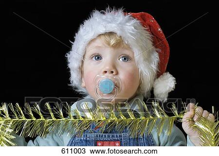 A boy wearing a Santa hat and holding tinsel View Large Photo Image Stock Image - A boy wearing a Santa hat and holding tinsel. Fotosearch