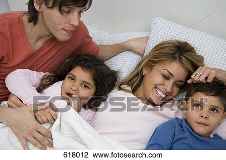 A family lying in bed together View Large Photo Image Stock Image - A family lying in bed together. Fotosearch
