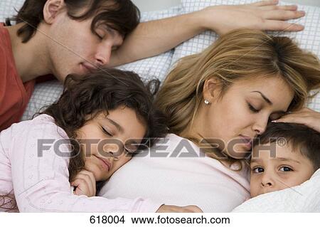 A family with two children sleeping in bed View Large Photo Image Picture - A family with two children sleeping in bed. Fotosearch