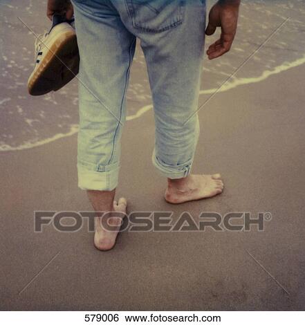 A man walking barefoot on the beach View Large Photo Image Stock Photograph - A man walking barefoot on the beach. Fotosearch