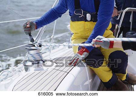 Stock Photography - A person turning a cable winch on a yacht. Fotosearch