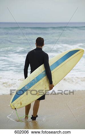 A surfer holding his surfboard View Large Photo Image Stock Photograph - A surfer holding his surfboard. Fotosearch