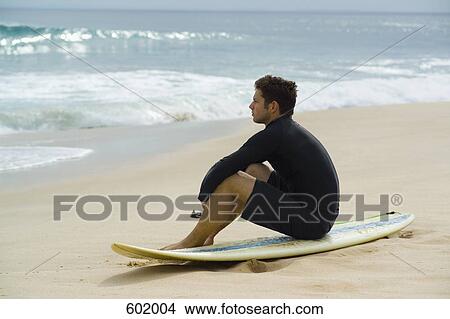 A surfer sitting on the beach View Large Photo Image Picture - A surfer sitting on the beach. Fotosearch