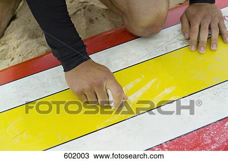 A surfer waxing his surfboard View Large Photo Image Stock Image - A surfer waxing his surfboard. Fotosearch