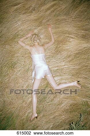 Stock Image - A woman lying in straw. Fotosearch