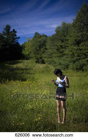 Stock Photograph - A woman standing in a field wearing old fashioned underwear. Fotosearch
