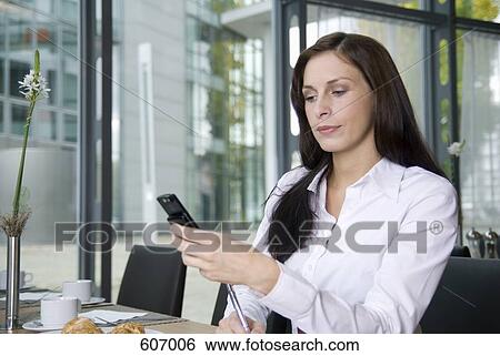 A woman using her mobile phone in a restaurant View Large Photo Image Stock Photograph - A woman using her mobile phone in a restaurant. Fotosearch