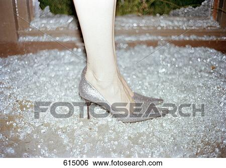 Stock Photograph - A woman wearing stilettos standing in broken glass. Fotosearch