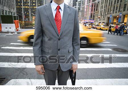 Midsection of a businessman standing in front of a pedestrian crossing View Large Photo Image Stock Photograph - Midsection of a businessman standing in front of a pedestrian crossing. Fotosearch