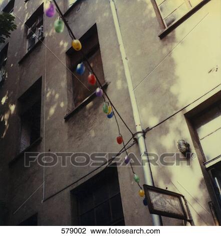 Stock Image - Multicolored lights hanging from a building. Fotosearch