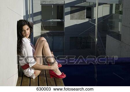 Portrait of a young woman sitting on the edge of a swimming pool View Large Photo Image Stock Image - Portrait of a young woman sitting on the edge of a swimming pool. Fotosearch