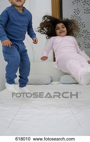 Two children jumping on a bed View Large Photo Image Stock Image - Two children jumping on a bed. Fotosearch