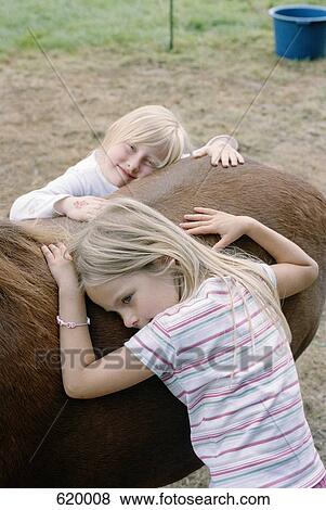 Two girls embracing a horse View Large Photo Image Stock Photo - Two girls embracing a horse. Fotosearch