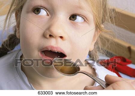 Stock Image - A human hand holding a spoonful of medicine for a young girl to swallow. Fotosearch