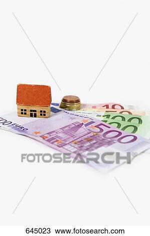 A miniature wooden house standing atop European banknotes View Large Photo Image Stock Image - A miniature wooden house standing atop European banknotes. Fotosearch