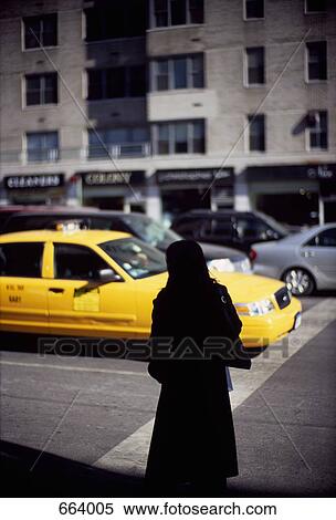 A silhouetted person standing on a city street as a yellow taxi drives by View Large Photo Image Stock Photography - A silhouetted person standing on a city street as a yellow taxi drives by. Fotosearch