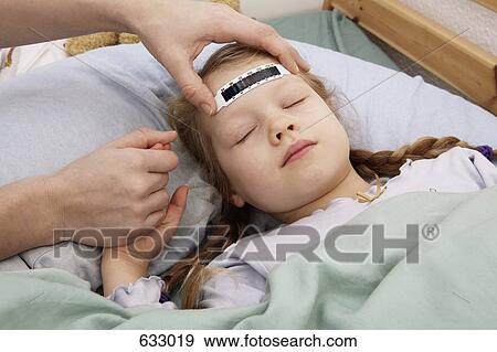 Stock Photo - A young girl having her temperature taken with a forehead thermometer strip. Fotosearch
