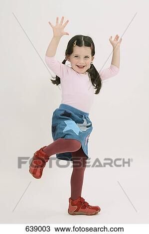 A young girl posing with her arms raised and one foot raised View Large Photo Image Stock Image - A young girl posing with her arms raised and one foot raised. Fotosearch