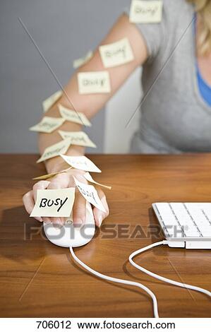 Stock Image - A human arm using a computer mouse with sticky notes on it that have the word busy written on them. Fotosearch