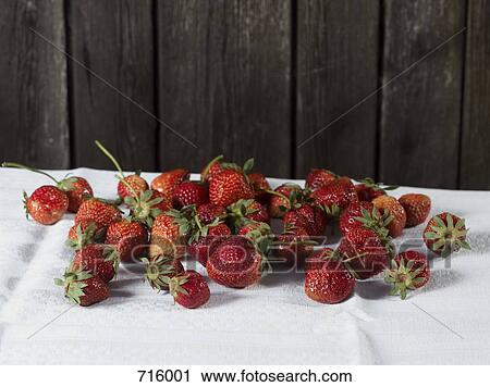 Stock Image - A large group of fresh strawberries on a white tablecloth. Fotosearch