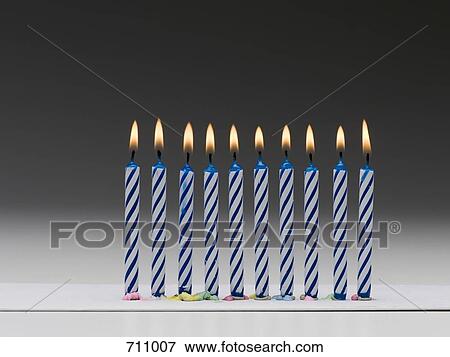 Stock Photo - A row of burning blue birthday candles. Fotosearch