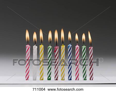 A row of burning multi colored birthday candles View Large Photo Image Picture - A row of burning multi colored birthday candles. Fotosearch