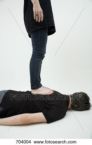 A woman standing on a man's back, obscured faces View Large Photo Image Picture - A woman standing on a man's back, obscured faces. Fotosearch