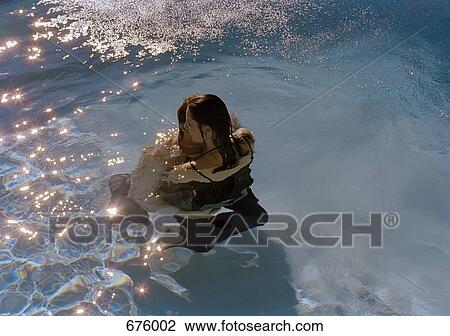 Stock Image - A young couple embracing in a swimming pool. Fotosearch