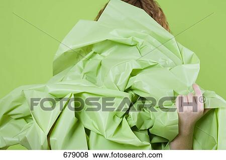 A young woman holding a large green paper in front of her View Large Photo Image Stock Photo - A young woman holding a large green paper in front of her. Fotosearch