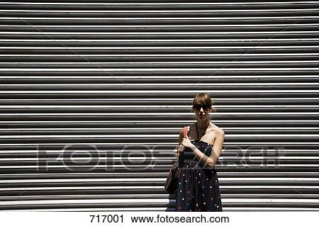 A young woman in front of metal shutter door View Large Photo Image Stock Image - A young woman in front of metal shutter door. Fotosearch