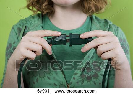 Stock Image - A young woman joining an electric plug to an extension cord. Fotosearch