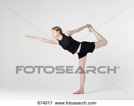 Stock Photo - A young woman practicing the 'Shiva' yoga pose. Fotosearch