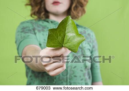 Stock Image - A young woman presenting an ivy leaf. Fotosearch
