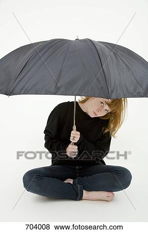 A young woman sitting cross legged under an umbrella View Large Photo Image Stock Photo - A young woman sitting cross legged under an umbrella. Fotosearch