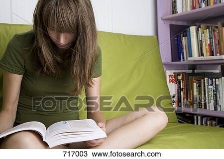 A young woman sitting on a couch reading View Large Photo Image Stock Image - A young woman sitting on a couch reading. Fotosearch