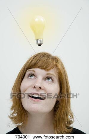 Stock Image - A young woman with a light bulb over her head. Fotosearch