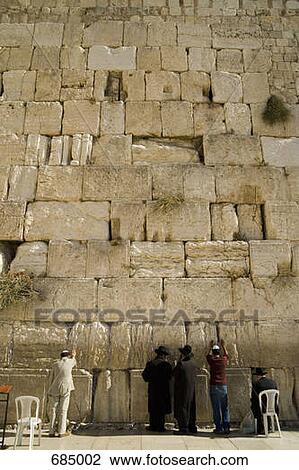 Stock Image - Five men praying at the Wailing Wall, rear view. Fotosearch