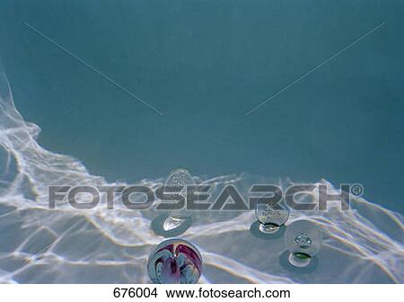 Four glass paperweights sitting at the bottom of a swimming pool View Large Photo Image Picture - Four glass paperweights sitting at the bottom of a swimming pool. Fotosearch