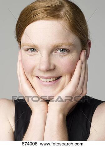Portrait of a young woman holding her face View Large Photo Image Stock Photograph - Portrait of a young woman holding her face. Fotosearch