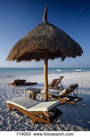 Sun loungers and straw parasol on a beach View Large Photo Image Stock Image - Sun loungers and straw parasol on a beach. Fotosearch