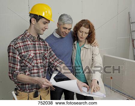 A building contractor going over blueprints with a young couple View Large Photo Image Stock Photo - A building contractor going over blueprints with a young couple. Fotosearch